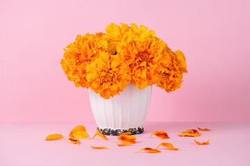 Marigold flowers in a white vase on a pink background. Autumn bouquet. Flowers for Day of the Dead and Indian holidays. copy space