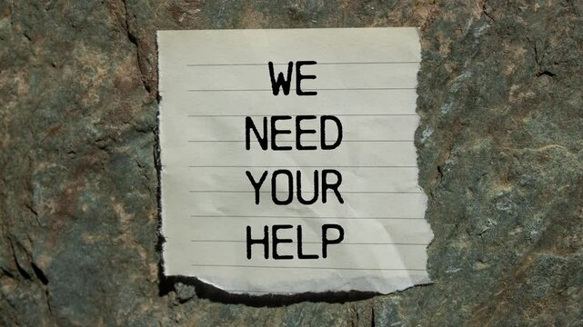 We need your help message writing on ripped torn paper on stone background. Conceptual we need your help symbol.
