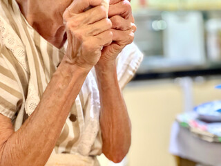 Obraz premium 口元で両手を握りしめる高齢女性