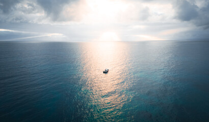 Obraz premium Beautiful landscape with a boat in the middle of the Ocean during sunset