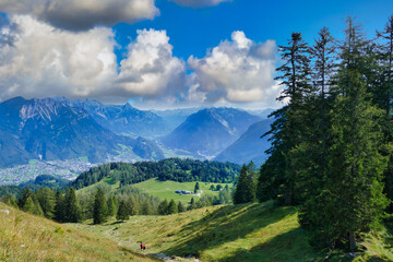 Obraz premium Alpine scenery with green meadows, pine forests and a deep valley. The town in the valley is Bludenz, Brandnertal, Vorarlberg, Austria 