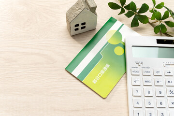 電卓と預金通帳とミニチュアの家