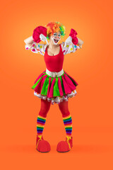 Funny female clown pointing down at blank template copy spase for advertising, posters, greetings, invitations. Entertainer as Joker in a suit and wig, with clown whiteface makeup