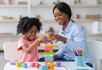 Adorable black kid curly little girl and child development specialist attractive young woman...