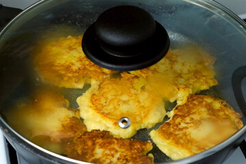 Potatoes pancakes, draniki cooking in frying pan on gas oven on kitchen at home. Preparing fresh dish. Cuisine, culinary, recipe. Traditional Russian food on lunch dinner fry on vegetable oil.