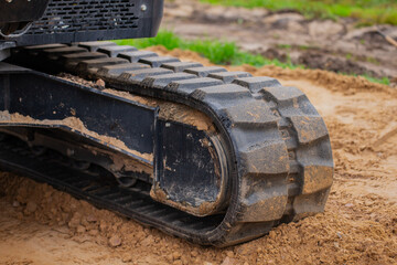 Construction excavator rubber track close up with rims full of rocks and mud after hard working...