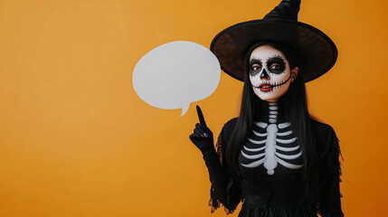 Young Beautiful Girl in Halloween Skeleton Costume and Witch's Hat with Cartoon Message Block on Yellow Background, Playful and Festive Scene