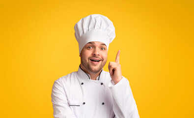 Great Recipe. Excited Chef Man Pointing Finger Up Having Idea Of A New Dish Standing On Yellow Studio Background. Panorama