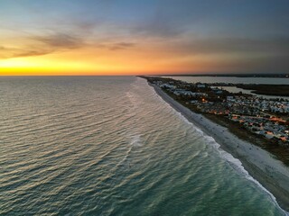Aerial view of coastal houses lining the beach stretching to the horizon at sunset. Florida