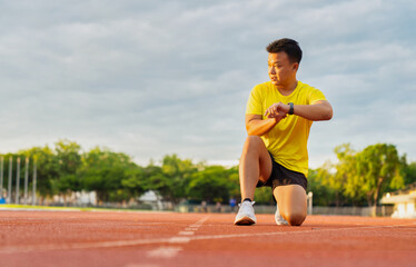 Fototapeta premium Male runner using smartwatch to track workout progress on the running track