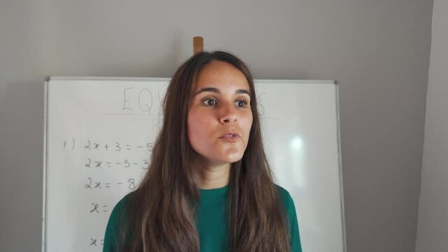 Portrait of brunette young girl teaching maths on a blackboard. Slow motion