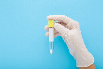Doctor hand in white rubber protective glove holding empty transparent plastic tube for urine or...