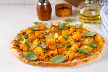 Homemade vegetarian vegetable pizza margarita with pumpkin sauce, pumpkin squash chunks and yellow tomatoes, autumn comfort warm food, copy space