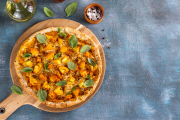 Homemade vegetarian vegetable pizza margarita with pumpkin sauce, pumpkin squash chunks and yellow tomatoes, autumn comfort warm food, copy space