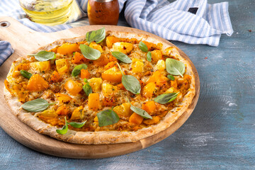 Homemade vegetarian vegetable pizza margarita with pumpkin sauce, pumpkin squash chunks and yellow tomatoes, autumn comfort warm food, copy space
