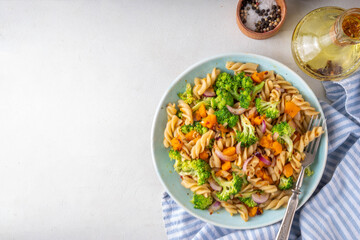 Pumpkin and broccoli vegan warm pasta salad, fall season salad, autumn comfort cozy food concept 
