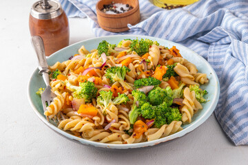Pumpkin and broccoli vegan warm pasta salad, fall season salad, autumn comfort cozy food concept 