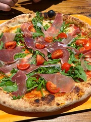 pizza with prosciutto close-up lunch with friends arugula and cherry tomatoes
