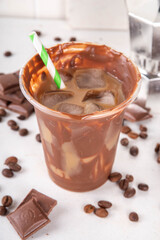 Viral Cracking Chocolate Latte drink. Plastic glass with cracked milk chocolate layer poured with iced latte, sweet coffee moccachino beverage