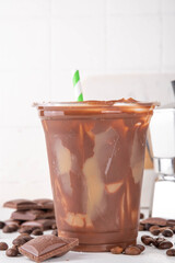 Viral Cracking Chocolate Latte drink. Plastic glass with cracked milk chocolate layer poured with iced latte, sweet coffee moccachino beverage