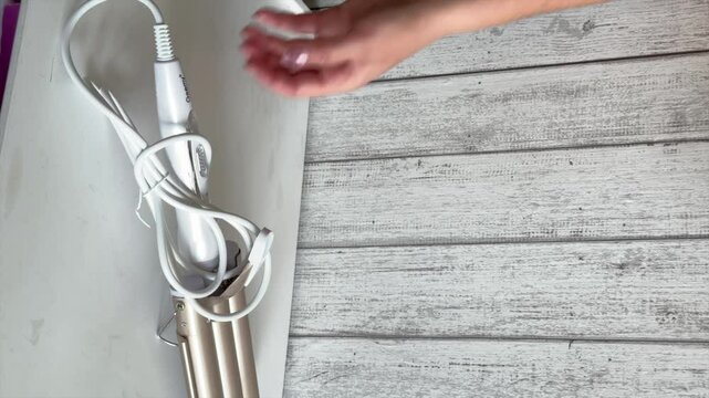 A woman is reviewing a purchase. Curling wand, hair styler. Close up. Vertical video.