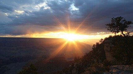 Naklejka premium Majestic Sunset Over Mountain Landscape with Sunbeams Piercing Through Dramatic Clouds