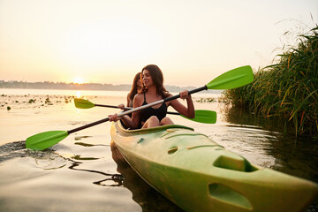 Together on the same boat. Women friends are on sup board on the lake