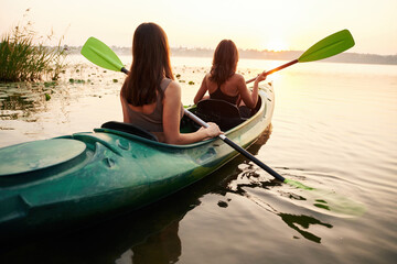 Together on the same boat. Women friends are on sup board on the lake