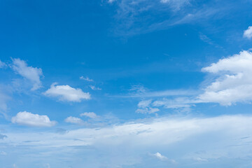 Beautiful fluffy white clouds drift across a clear blue sky