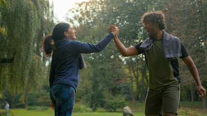Indian woman sport Arabian man give high five active sportive fit couple rejoice celebrate success exercise fitness training workout excited friendship happy with sporting achievement teamwork in park