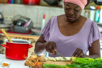 Cooking - womans hands preparing chicken stock broth or bouillon with vegetables in a pot. Kitchen - scenery