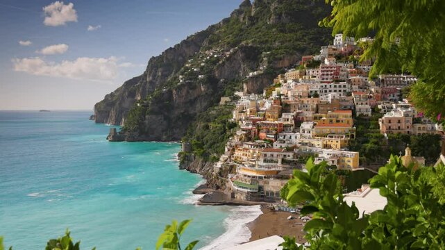 Beautiful Positano village, Amalfi coast, Italy. Camera moves between green leaves, overlooking the beach with turquoise water, colorful houses and mountains in Positano village. Steadycam shot, 4K
