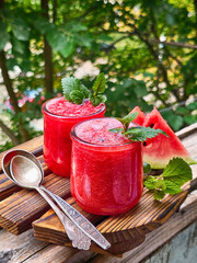 Watermelon smoothie with mint and chocolate topping on wooden background