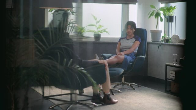 African American teenage girl on counseling session with psychologist. Back view of female psychotherapist sitting in chair and listening. Teen patient talks about problems, discusses family issues.