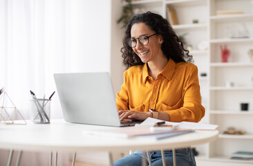 Happy Middle Eastern Businesswoman Using Laptop Typing And Working Online Sitting At Workplace...