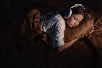 Fototapeta premium Teen girl peacefully sleeping on a pillow with headphones on, creating a serene and relaxed atmosphere