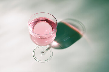 Pink jelly pudding in a wine glass illuminated by the morning sunlight from the window
