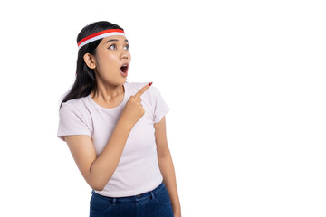 Surprised young Asian woman pointing at copy space, showing advertisement isolated on white background. Indonesian Independence Day Celebration Concept