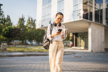 Mature japanese business woman use mobile phone in front of buildings