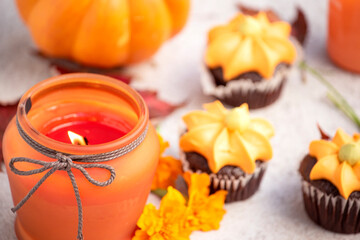 Pumpkin cupcakes, autumn leaves, orange candles and pumpkins on a light background. autumn holidays halloween and thanksgiving.