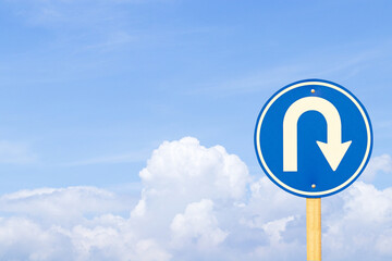 U turn sign blue for motorbike, car side street. Rules for road users. It's traffic sign. White cloud sky,  sun light background. In nature daylight. Bold white symbol arrow indicating maneuver.