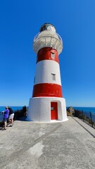 Fototapeta premium A traditional striped red and white lighthouse with a blue sky background