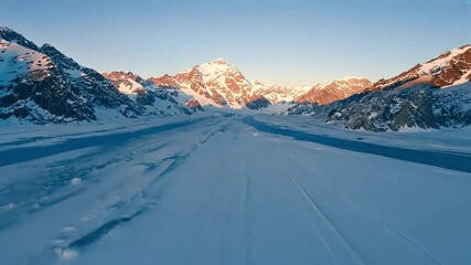 Snowy mountains reflecting perfectly in a still lake at sunset