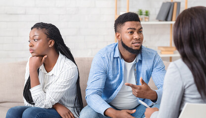 Afro Husband Sharing Family Problems Sitting Next To His Offended Wife At Counselor's Office,...