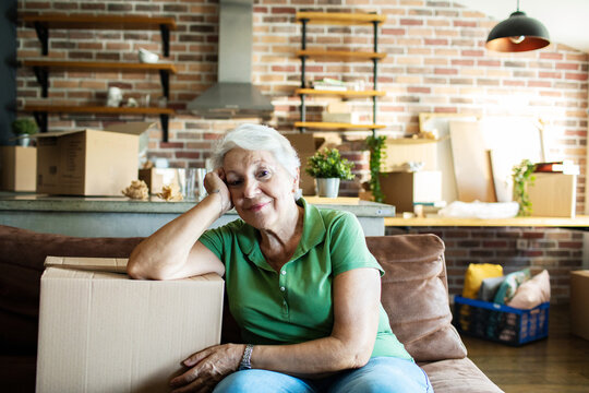 Portrait of a senior woman sitting on couch with moving boxes in new home