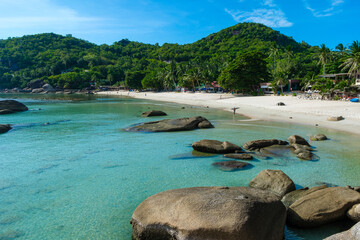 A beach with a large rock formation and a few people in the water, Silver beach, kohsamui