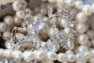 Close-up of an elegant assortment of jewelry, including pearl necklaces and silver diamond-studded pieces. This image captures the luxury and intricacy of fine jewelry, showcasing the beauty and
