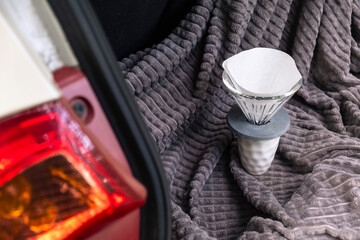 Coffee filter in the car. Making coffee outdoors. White cup on a blanket. Filter. White car. Coffee on the road