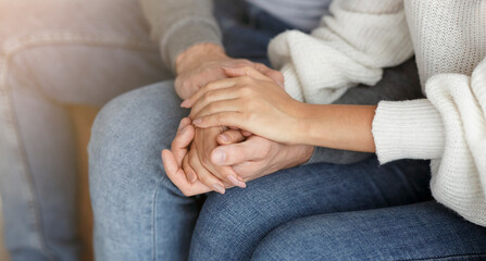 Happy Reconciliation. Unrecognizable Couple Holding Hands Sitting On Couch During Family Therapy Session Indoor. Cropped, Selective Focus