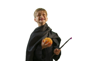 A wizard boy with a magic wand in a Halloween costume